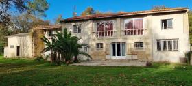 Maison en pierre sur un terrain arboré avec petit étang poissonneux